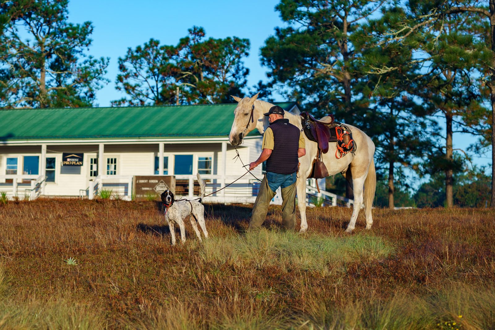 Handler leading an English setter and white horse past the J. Robert Gordon Field Trial Grounds clubhouse
