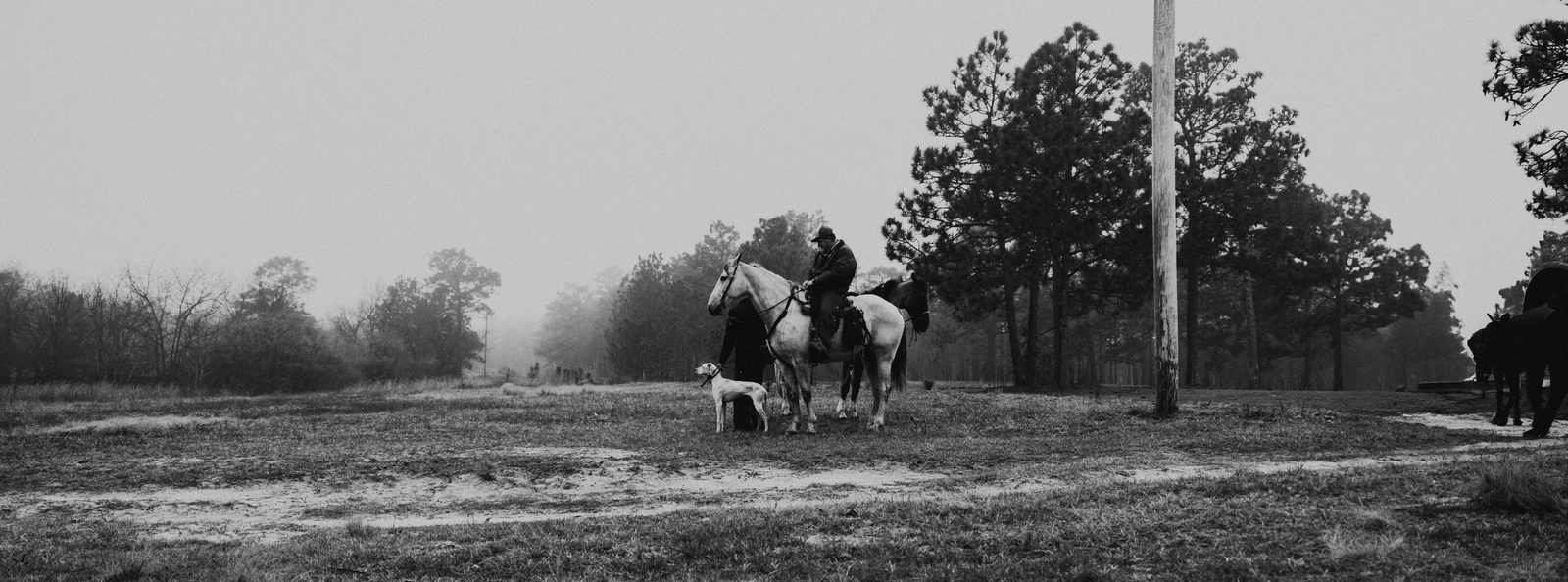 Two mounted judges with a pointer in front of the field trial clubhouse, black and white