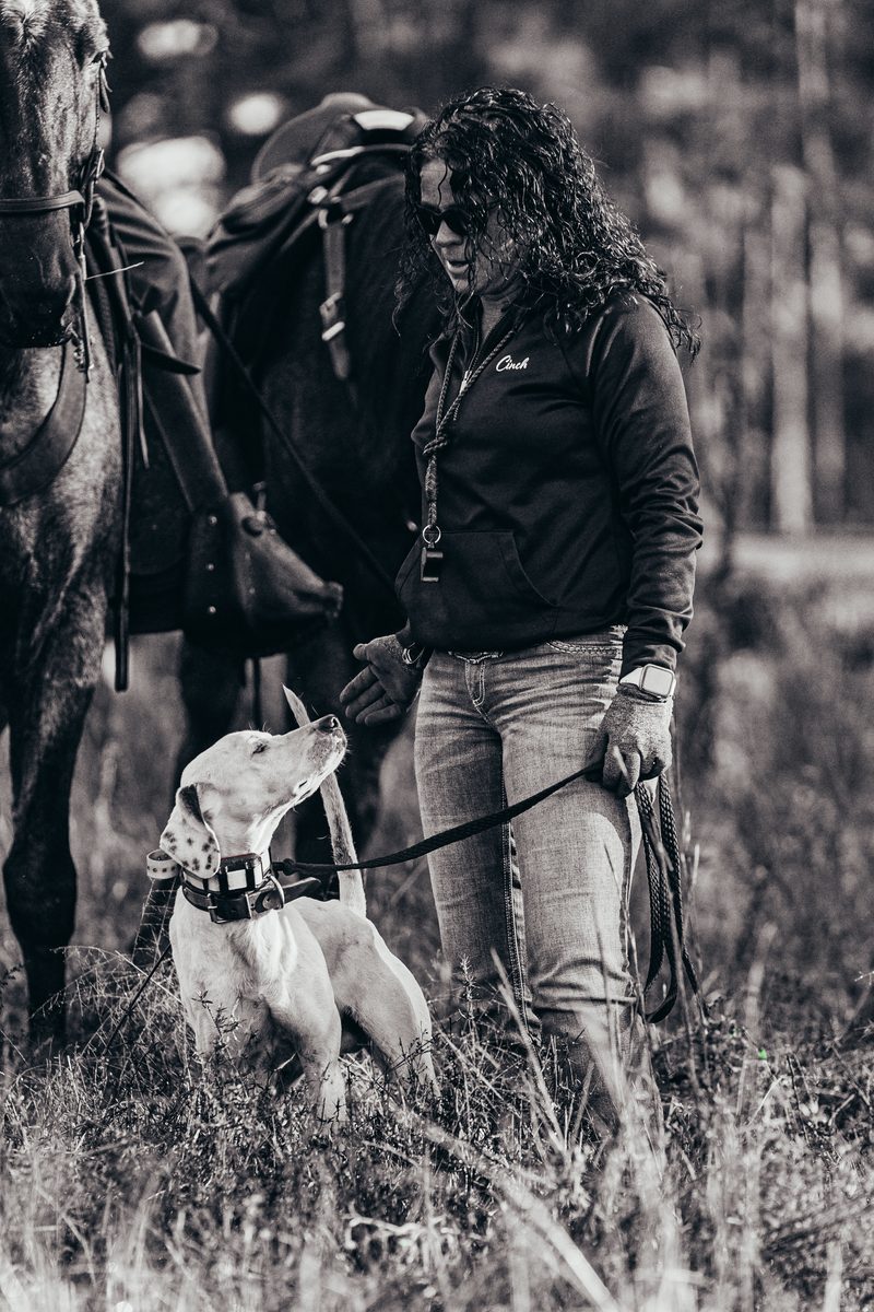 Woman handler in Cinch jacket with her pointer at her side, black and white portrait